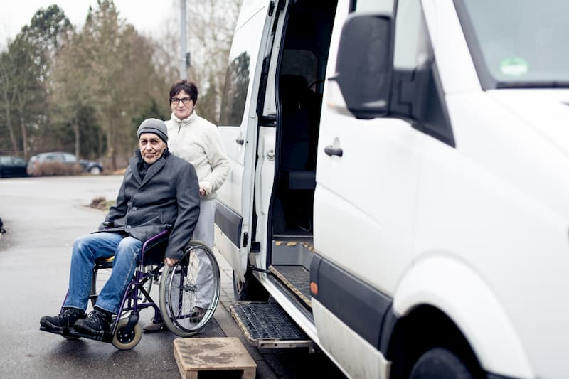 Eine Frau bei einer Taxifahrt mit einem Menschen im Rollstuhl, ein potenzieller Job für Rentner