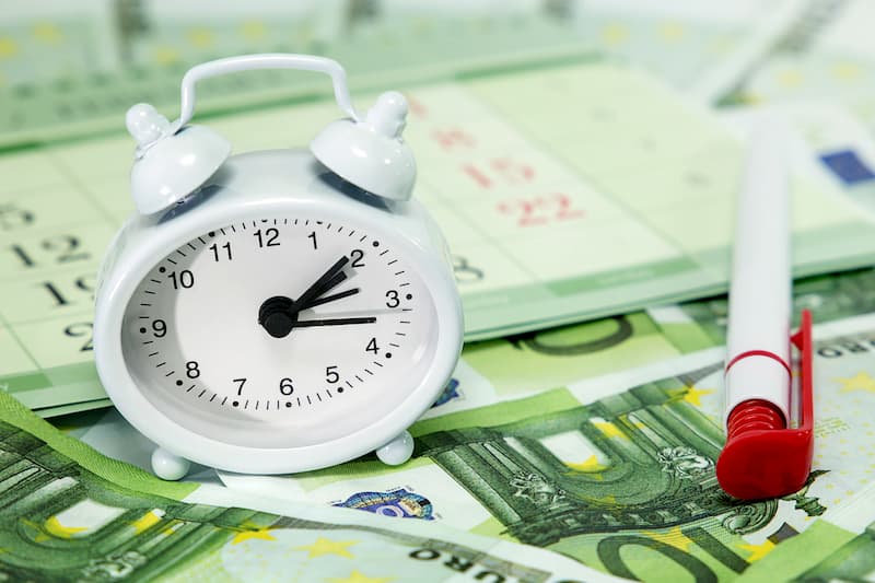 Eine Uhr auf Geldscheinen, was ist ein Zeitlohn?