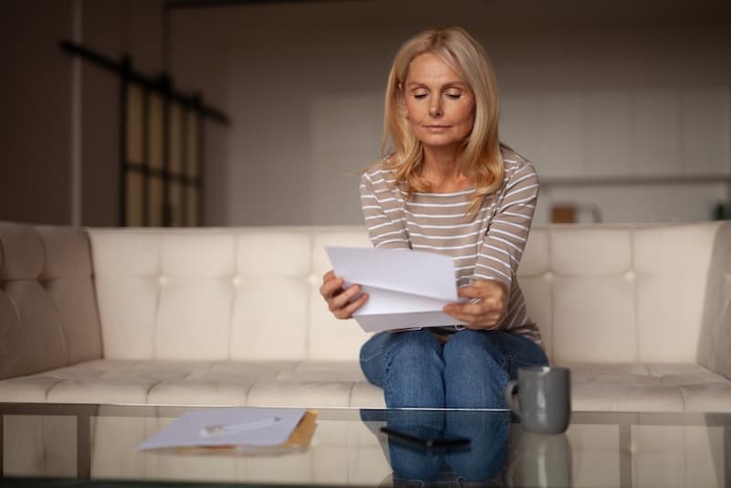 Eine Frau liest einen Brief, ist man bei Arbeitslosigkeit krankenversichert?