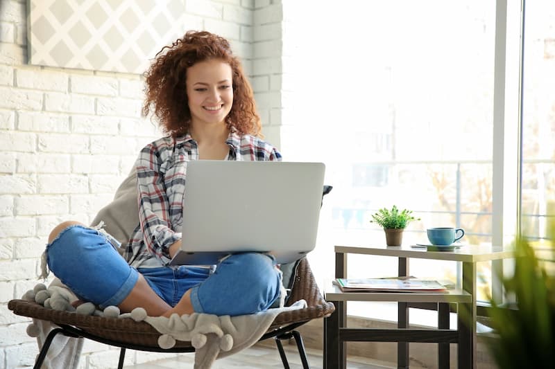 Eine Frau arbeitet Zuhause am Laptop, sie hat einen Online-Nebenjob