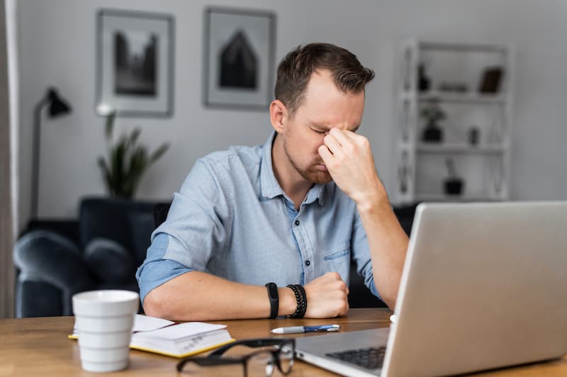 Ein Mann sitzt frustriert vor dem PC, was steht in einem Burnout-Selbsttest?
