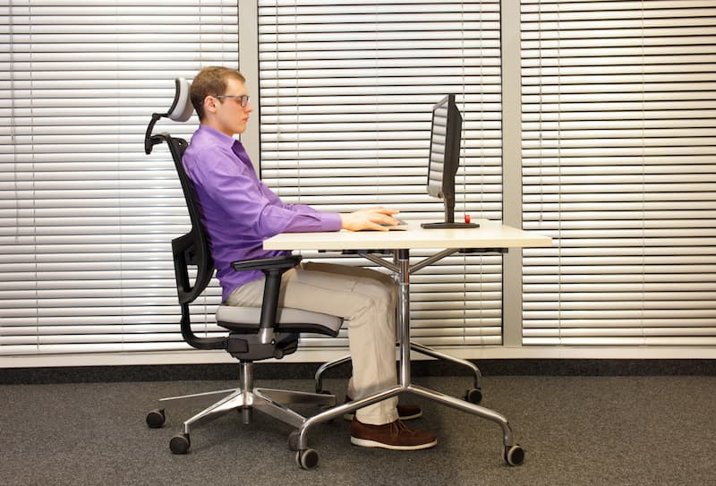 Ein Mann sitzt am Schreibtisch, was steckt hinter der Ergonomie am Arbeitsplatz?