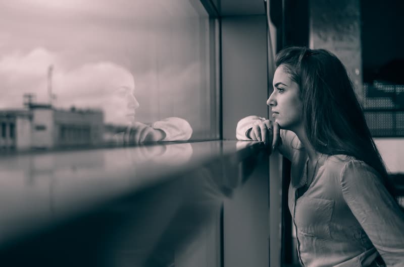 Eine Frau blickt gedankenvoll aus dem Fenster, was ist Selbstreflexion?