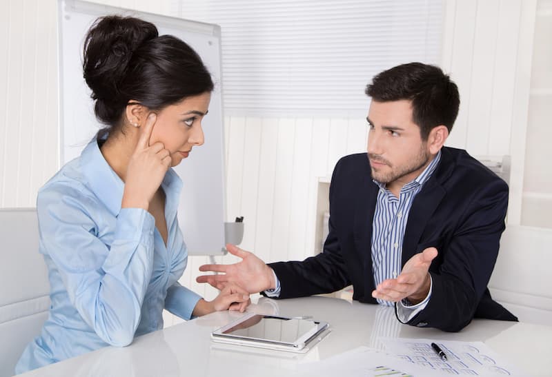 Ein Chef im Gespräch mit einer Mitarbeiterin, was sind faire Kritikgespräche?