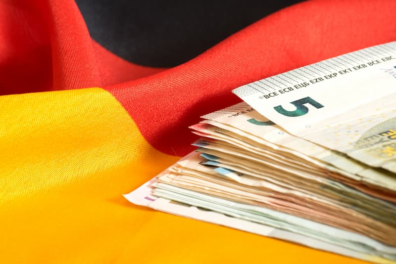 Geldscheine auf einer deutschen Flagge, was ist die Arbeitnehmersparzulage?