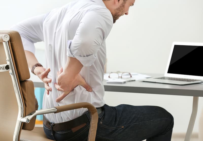 Ein Mann mit Rückenschmerzen, wann kann man nach Arbeitsunfall wieder arbeiten?