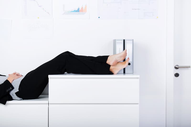 Eine Frau schläft im Büro, wie funktioniert der Umgang mit schwierigen Mitarbeitern?